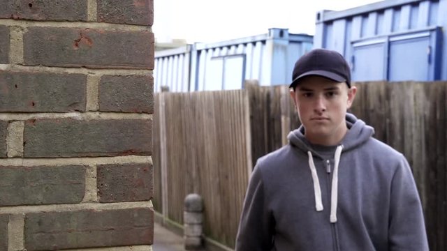 Portrait Of Teenage Boy Leaning Against Wall In Urban Setting   