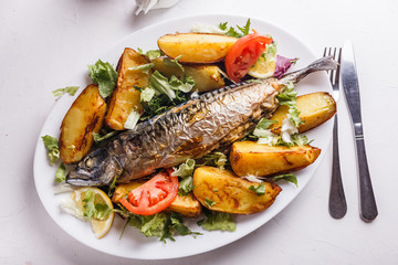 Baked stuffed fish with potatoes on the plate