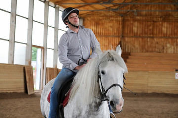 People on a horse training in a wooden arena