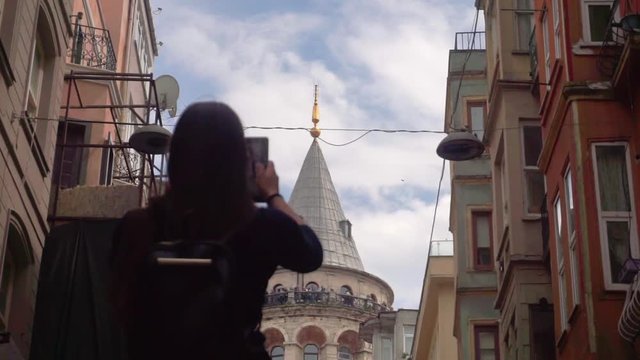 Girl tourist stands with a tablet in his hands and takes pictures of a beautiful tower attraction