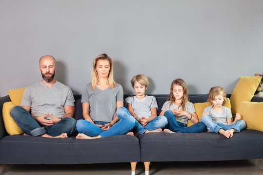 Family sitting in meditation. Father and mother with children sitting in pose of lotus with their eyes closed and meditating.Family yoga concept