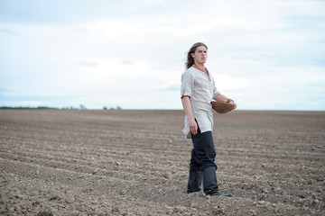 A young peasant sows the field with grain