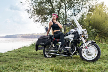 Fototapeta na wymiar Beautiful young woman posing with motorcycle outside