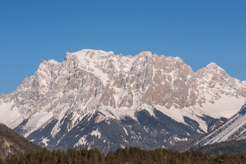 Fototapeta na wymiar Germany highest mountain the Zugspitze..In winter, the mountain is full of beauty, with many trees in the valley and snow on top of the mountain.