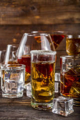 Assortment various hard and strong alcoholic drinks in different glasses: vodka, cognac, tequila, brandy and whiskey, grappa, liqueur, vermouth, tincture, rum, etc. Wooden background copy space