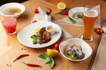 German-style lunch with bratwurst, mashed potato, soup and appetizer with herring, served on a craft paper covered table
