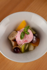 Fruit salad with a scoop of strawberry ice cream