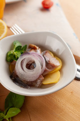 Close up of an appetizer with herring, red onion and boiled potato