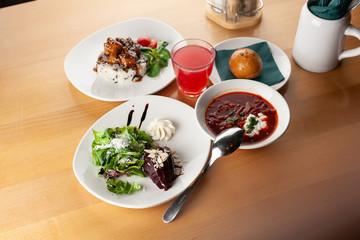 Three course set menu in russian style: beetroot borscht, beetroot salad with goat cheese and steamed rice with gravy