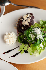Close up of a vegetarian beetroot salad with greens, almond and goat cream cheese for a healthy dinner
