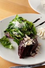 Close up of a vegetarian beetroot salad with greens, almond and goat cream cheese for a healthy dinner