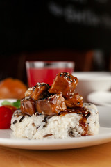 Pork goulash with vegetables and steamed rice on a white plate and wooden rustic table