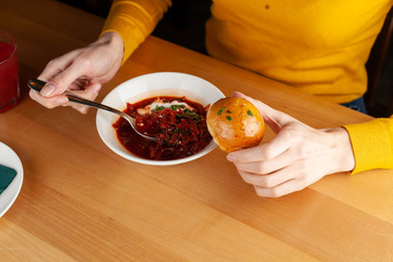 Woman is eating traditional russian beetroot borscht with garlic bread