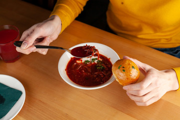 Woman is eating traditional russian beetroot borscht with garlic bread