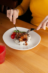 Woman is eating a traditional hungarian pork goulash with vegetables and steamed rice