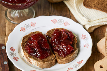 Slices of rye bread with plum jam on a wooden table