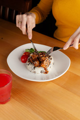 Woman is eating a traditional hungarian pork goulash with vegetables and steamed rice