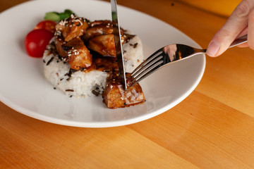 Woman is eating a traditional hungarian pork goulash with vegetables and steamed rice