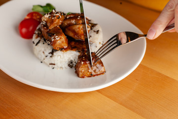 Woman is eating a traditional hungarian pork goulash with vegetables and steamed rice