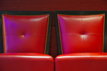 Zwei rote Ledersessel vor roter Wand