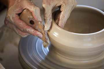 Fototapeta premium Close up of female hands shaping clay on potters wheel while working in studio, copy space
