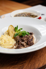 Classic russian beef stroganoff with white gravy and mashed potatoes served in a white plate