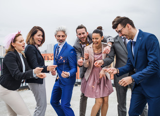 A group of joyful businesspeople having a party outdoors on roof terrace in city.