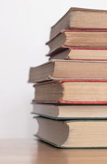 Pile of old dusty books on a wooden surface