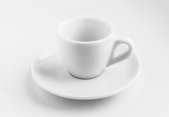white empty coffee cup with saucer standing on a white background, contrasting clear shadows from it, business concept, white dishes for coffee