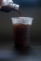Pouring coffee into a glass with ice cube