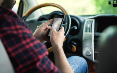 a young man at the wheel uses the phone as a navigator