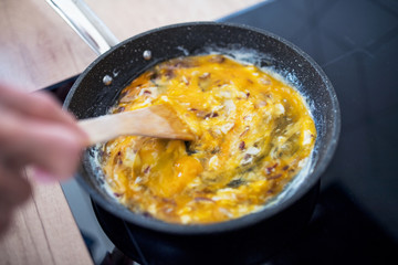 A close-up of cooking scrambled eggs on pan at home.