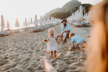 Young family with toddler children having fun on beach on summer holiday.