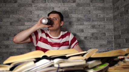 Young man drinking energy drink while studying. College student concept. Energizing before learning