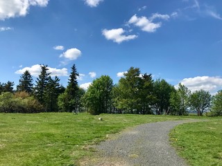 Scenic hike to the Kreuzberg (Calvary) in the Bavarian Rhoen region (Germany) on a beautiful sunny summer day through lush green landscape with grass, trees and a blue sky with white clouds
