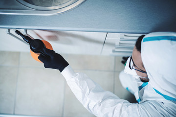 Exterminator in work wear spraying pesticide with sprayer. Selective focus.