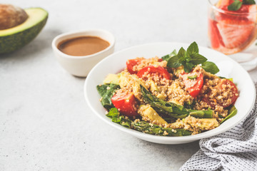 Green salad with quinoa, avocado and asparagus in a white bowl.