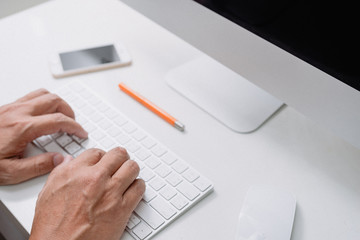 hand typing white computer keyboard of desktop computer on White desk