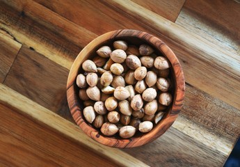 Hazelnuts in a walnut bowl on a wooden table - top view