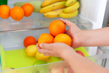 Woman getting some fresh oranges from fridge