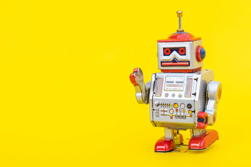 Antique tin toy robot on yellow background. Vintage and classic concept free copy space for text.