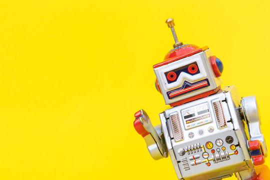 Antique tin toy robot on yellow background. Vintage and classic concept free copy space for text.