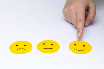 Cut out of paper mood emoticons on a white background. The finger of the hand indicates the chosen mood.