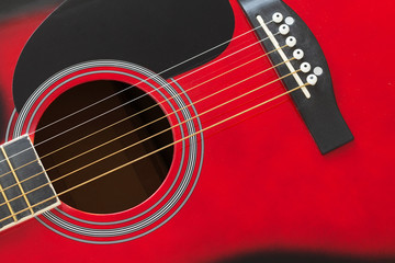 Fototapeta na wymiar Closeup of a six stringed red acoustic guitar. Music entertainment background.
