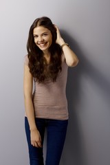 Happy young woman posing by grey wall