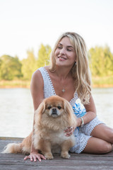 Nice blonde woman with her dog on a lake, concept of love to pets. Friendship human and animals 