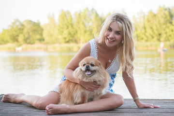 Nice blonde woman with her dog on a lake, concept of love to pets. Friendship human and animals 