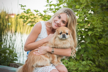 Nice blonde woman with her dog on a lake, concept of love to pets. Friendship human and animals 
