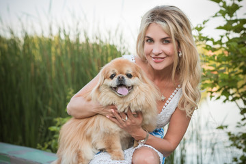 Nice blonde woman with her dog on a lake, concept of love to pets. Friendship human and animals 