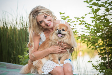 Nice blonde woman with her dog on a lake, concept of love to pets. Friendship human and animals 